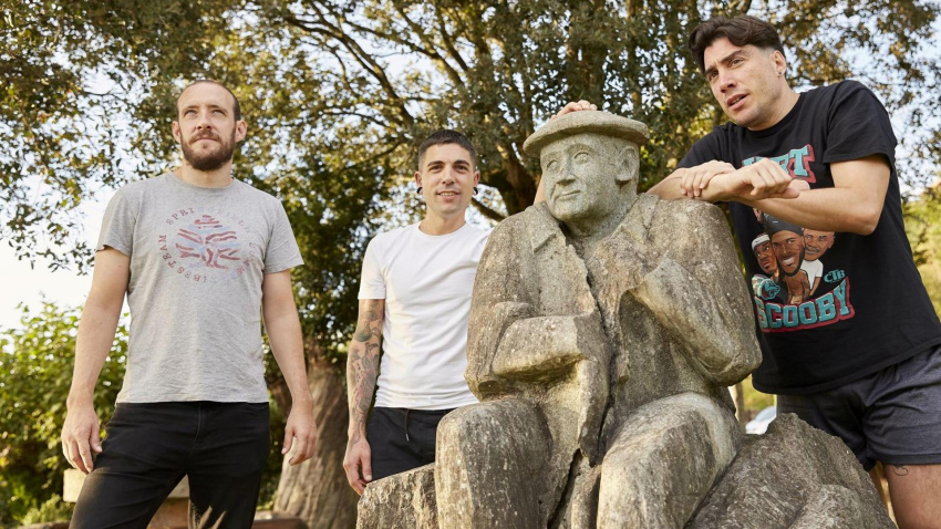 Julen Baz, Eneko Axpe y Jon Sola junto a la estatua del aizkolari Julián Larrea, atravesada por un rayo.