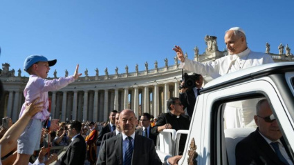 El pontífice saluda a un niño en su entrada en la plaza de San Pedro junto a la columnata de Bernini