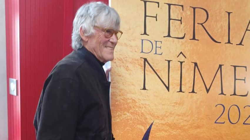 Simón Casas junto al cartel anunciador de la Feria de Pentecostés de Nimes