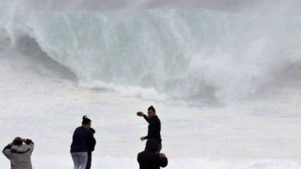 Dos turistas observan las olas en la costa en Muxía, un día de temporal. EFE