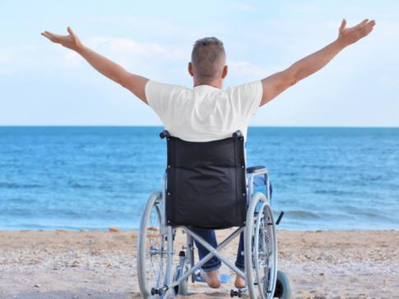 Una persona en silla de ruedas en la playa frente al mar