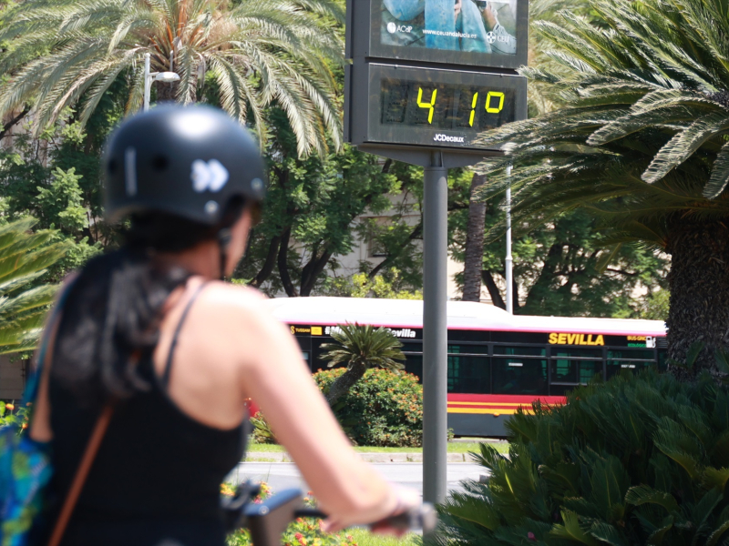 Una joven se resguarda del sol con un abanico para soportar las altas temperaturas en Sevilla