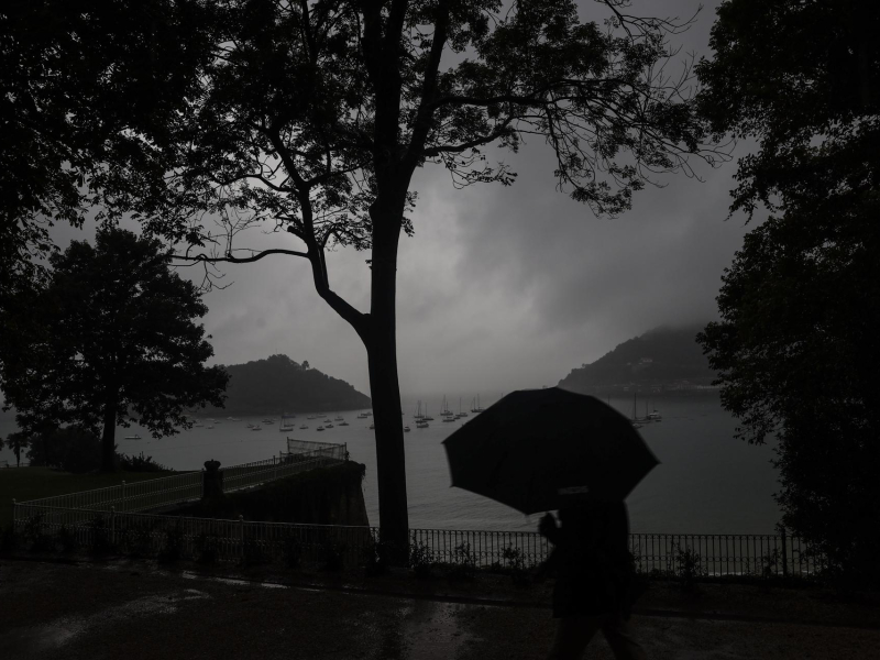 Un hombre se protege con el paraguas de una fuerte tormenta en el paseo de la Concha de San Sebastián