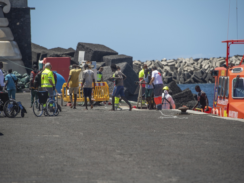 Varios migrantes desembarcan de un cayuco, en el puerto de La Restinga