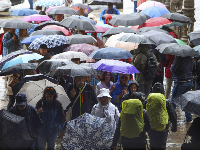 Peregrinos y turistas se protegen de la lluvia en la plaza del Obradoiro en Santiago de Compostela