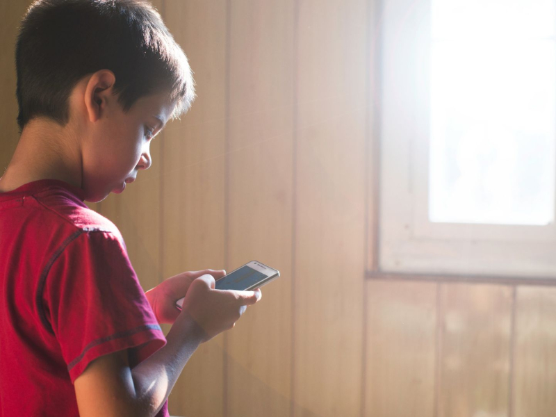 Un niño joven con un teléfono móvli