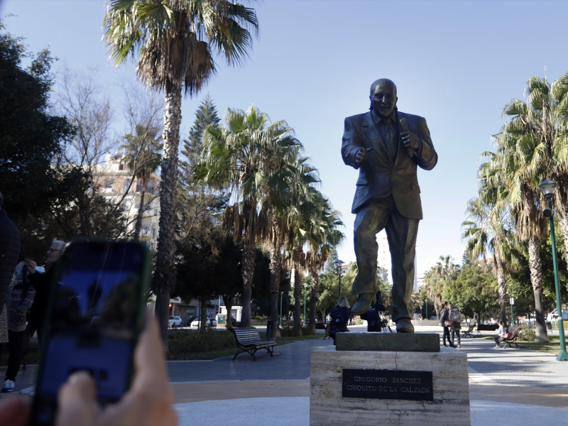 Una persona fotografía la estatua de Chiquito de la Calzada en Málaga