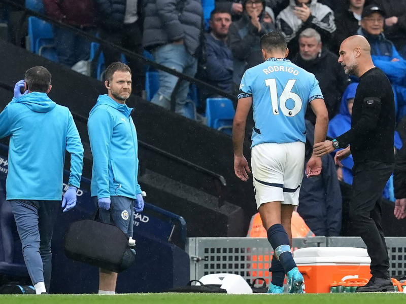 Guardiola habla con Rodrigo tras su salida del campo con la lesión.