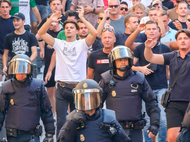 Funkcjonariusze policji krajowej eskortują kibiców Feyenoordu przez centrum Madrytu