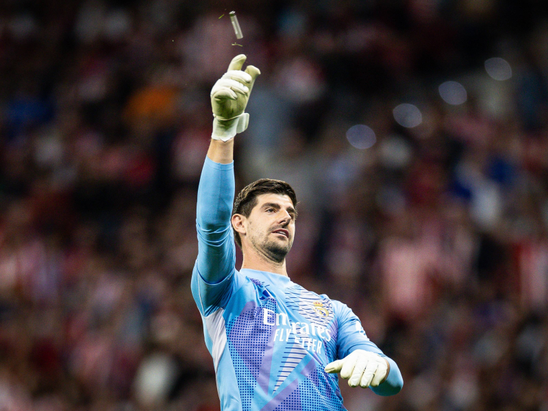 Courtois retira del terreno de juego uno de los mecheros que le lanzaron durante el derbi.