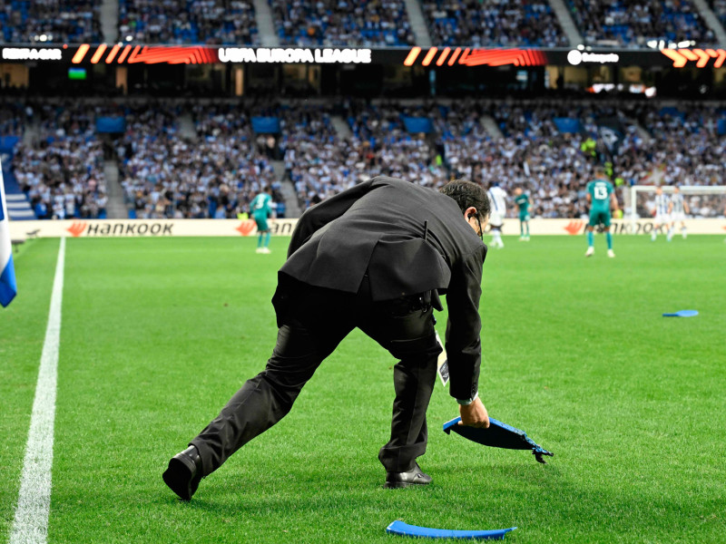 Un trabajador recoge trozos de sillas lanzados por ultras del Anderlecht al césped del Reale Arena