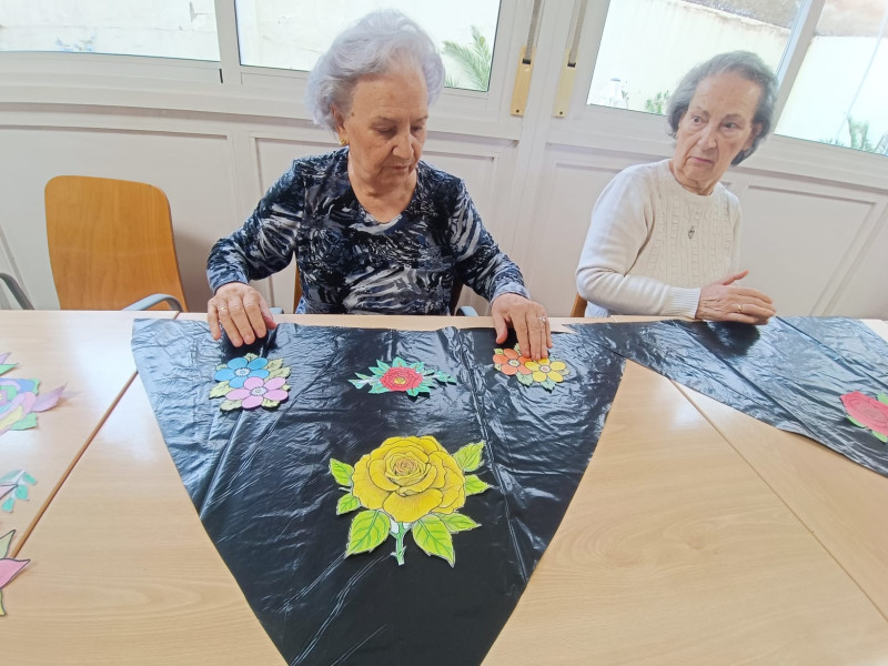 Rosario, a la derecha, confeccionando su manto de flores