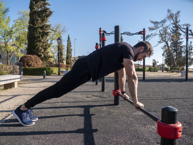 Un joven caucásico de España entrenando calistenia en un parque en un día soleado de primavera