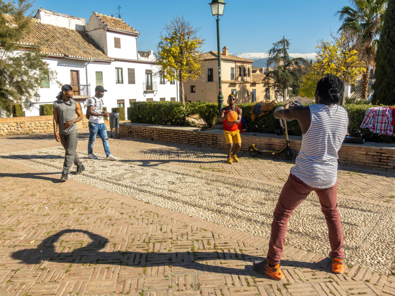 Cuatro jóvenes negros jugando al baloncesto en un lugar espontáneo del centro histórico de Granada en San Nicolás, Andalucía, España