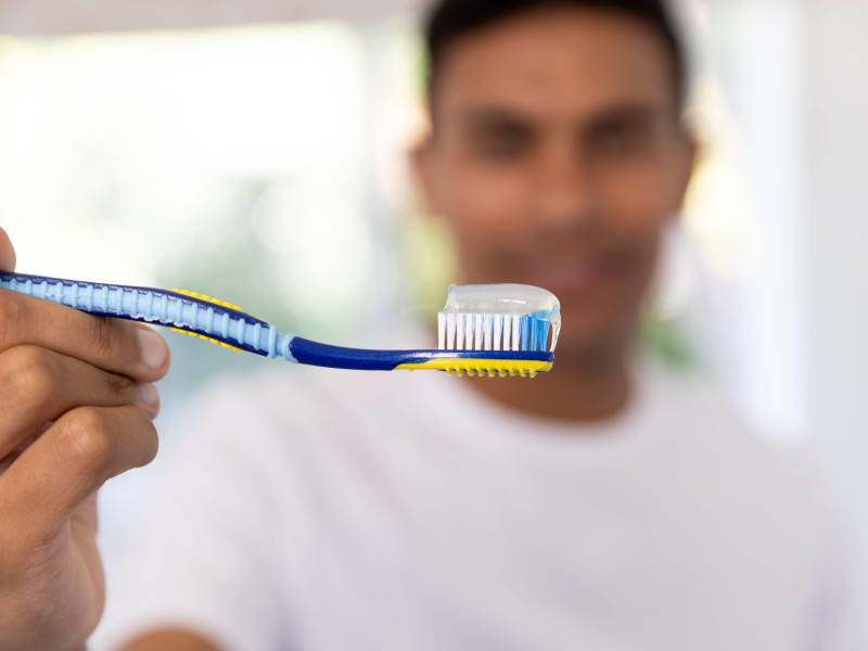 Hombre feliz sosteniendo un cepillo de dientes en el baño en casa