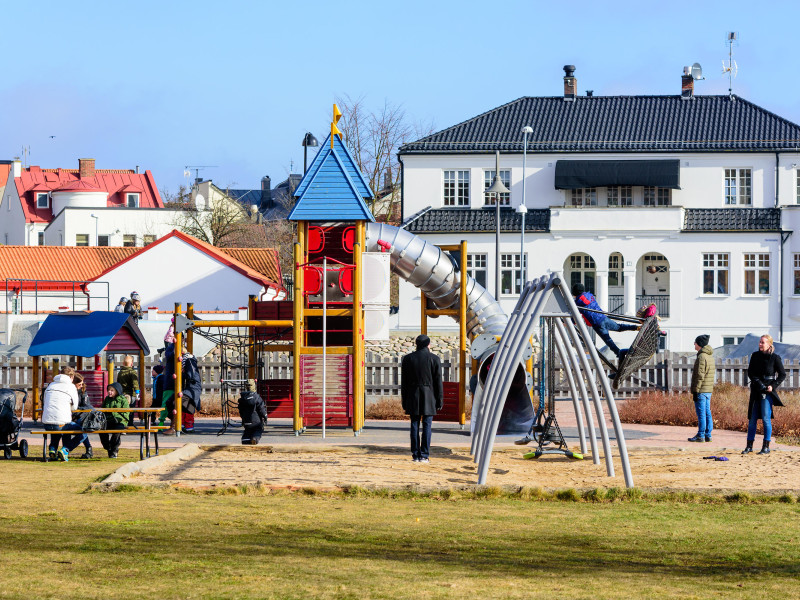 Un parque infantil en la ciudad con muchos niños y adultos divirtiéndose juntos en primavera.