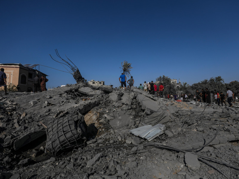 Palestinos buscan entre los escombros de una casa destruida tras los ataques aéreos israelíes en el campo de refugiados de Al-Maghazi, Franja de Gaza, 17 de octubre de 2024