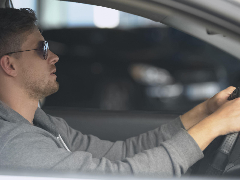 Conductor masculino que lleva gafas de sol polarizadas para proteger los ojos y conducir de forma segura