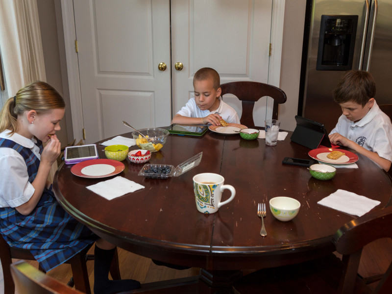 Estudiantes de una escuela primaria moderna desayunando y jugando en sus iPads