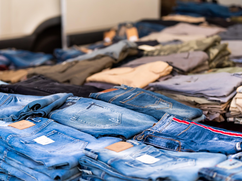 Patrón de primer plano de muchos pantalones vaqueros azules de diseñador doblados en exhibición en un mercado callejero comercial