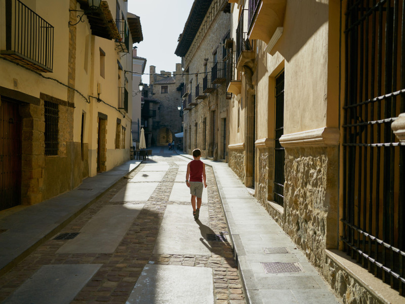 Un niño camina por un callejón con casas antiguas en Mora de Rubielos, Teruel, España