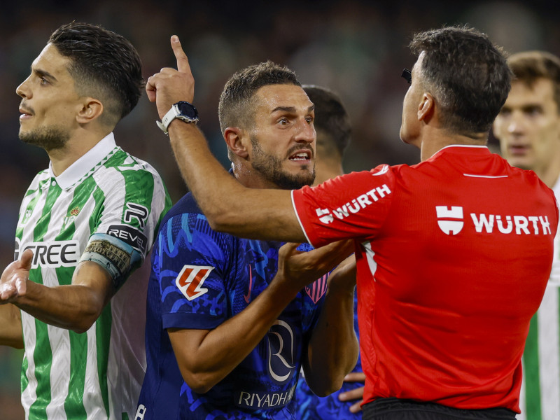 El árbitro Gil Manzano (d) conversa con el centrocampista español del Atlético de Madrid Koke Resurrección (c) durante el encuentro correspondiente a la jornada 11 de Laliga EA Sports que disputan hoy domingo Betis y Atlético de Madrid en el estadio Benito Villamarin, en Sevilla