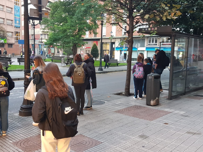 Usuarios del bus urbano esperando en una parada de EMTUSA, en Gijón