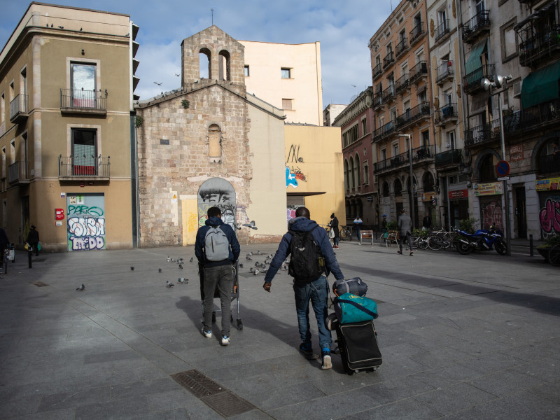 Dos sintecho arrastran carritos y maletas en el barrio del Raval