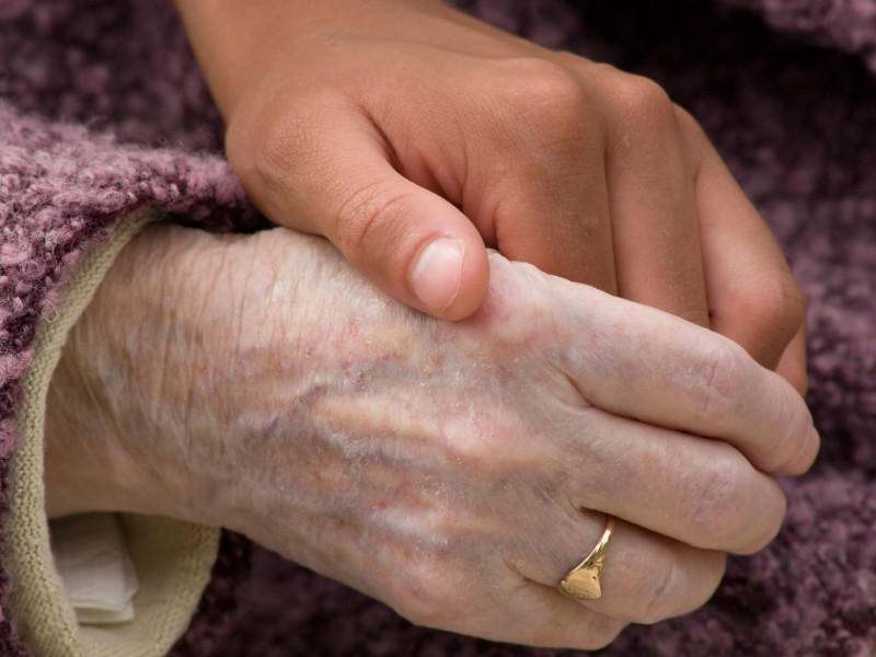 Primer plano de la mano de una mujer joven que sostiene la mano de una anciana