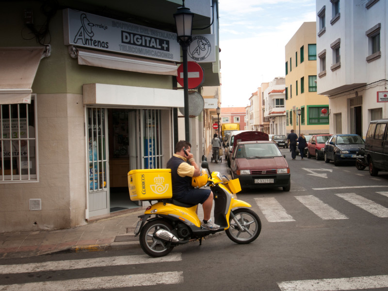 Listonosz na motocyklu odbierający telefon na swoim telefonie komórkowym Fuerteventura