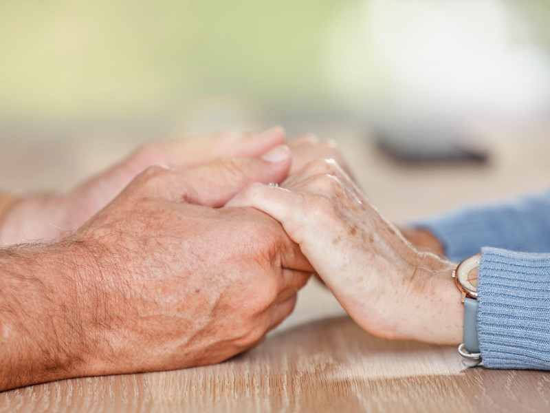 Una pareja de ancianos tomados de la mano en señal de amor, apoyo y confianza durante la jubilación, el asesoramiento y el matrimonio