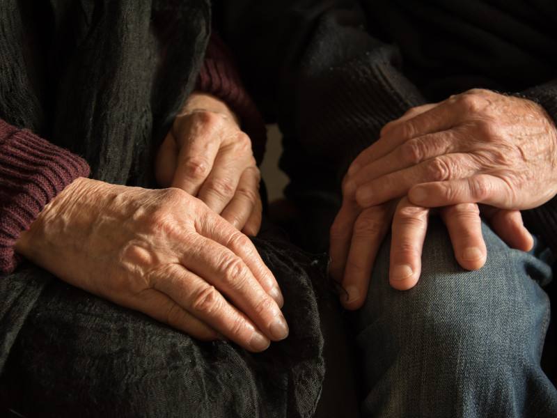 Manos de una anciana y un anciano sentados juntos