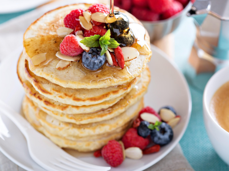 Panqueques de avena esponjosos con bayas frescas, café y almíbar