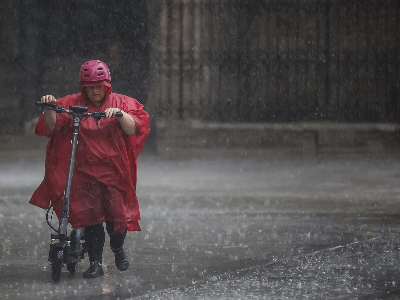 Una mujer circula con su patinete durante las lluvias