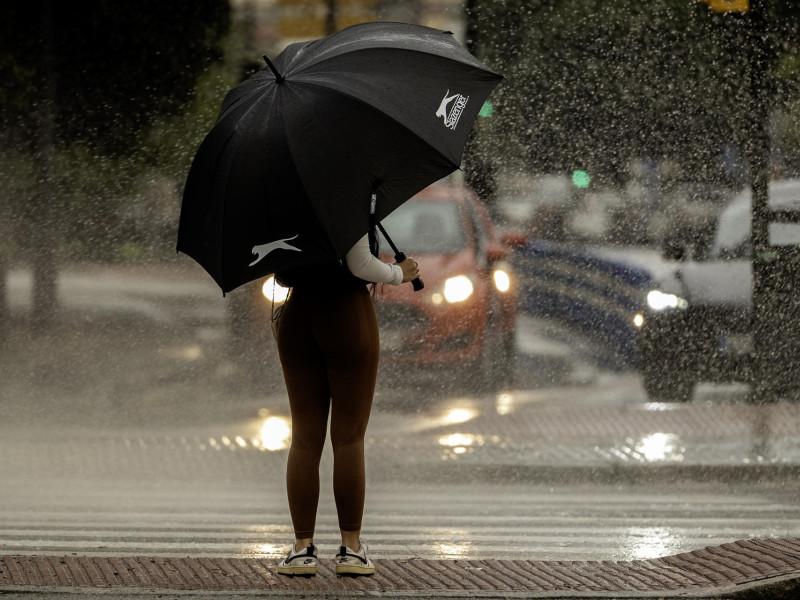 Una mujer se resguarda de la lluvia bajo un paraguas este martes en Málaga