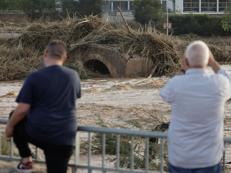 Varios vecinos contemplan el puente arrastrado por el agua en Ribarroja del Turia (Valencia), tras las intensas lluvias de la fuerte dana que afecta especialmente el sur y el este de la península ibérica, este miércoles