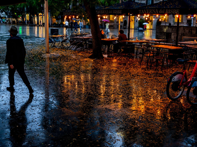 Barcelona, ​​España: Las luces de la terraza de un bar se reflejan en el suelo del casco antiguo de Barcelona después de un diluvio al anochecer.