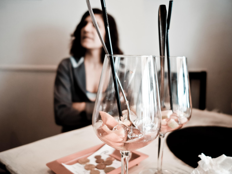 Mujer en un bar esperando, dos vasos vacíos de sangría en primer plano, con la cuenta pagada al lado, España.