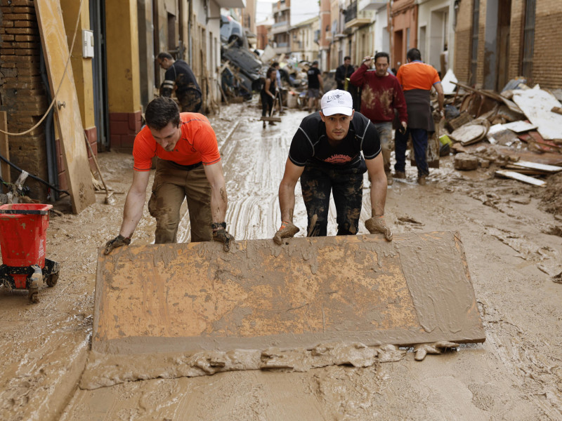 Vecinos de Paiporta limpian el lodo de una calle afectada,