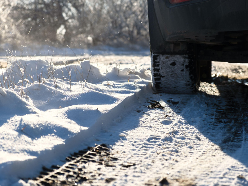 Primer plano de las ruedas de un coche sobre la nieve. Conducción por una carretera de invierno. Neumáticos de invierno fotografiados desde un ángulo inferior