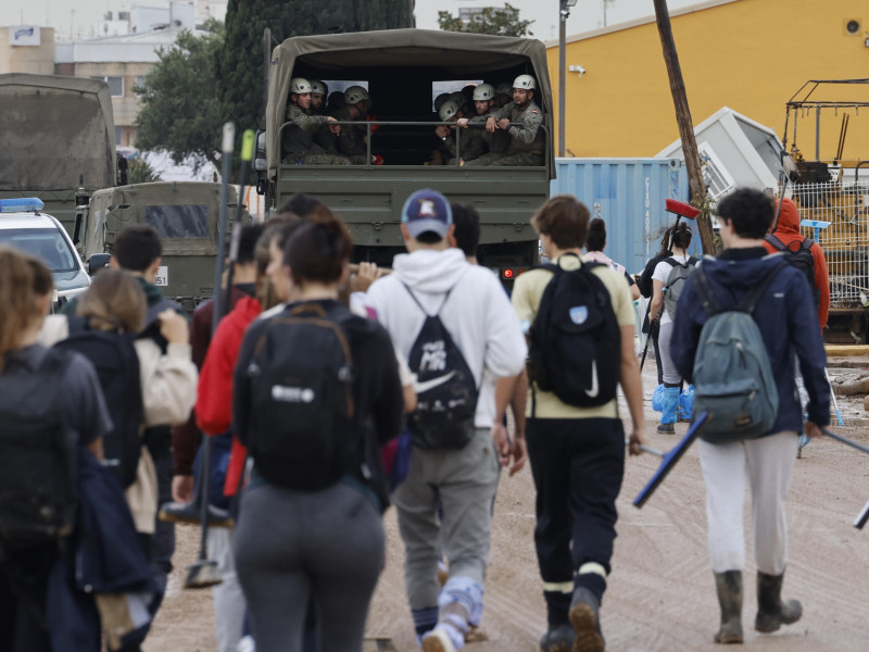 Un grupo de peronas junto con un camión del Ejército caminan en dirección a Paiporta