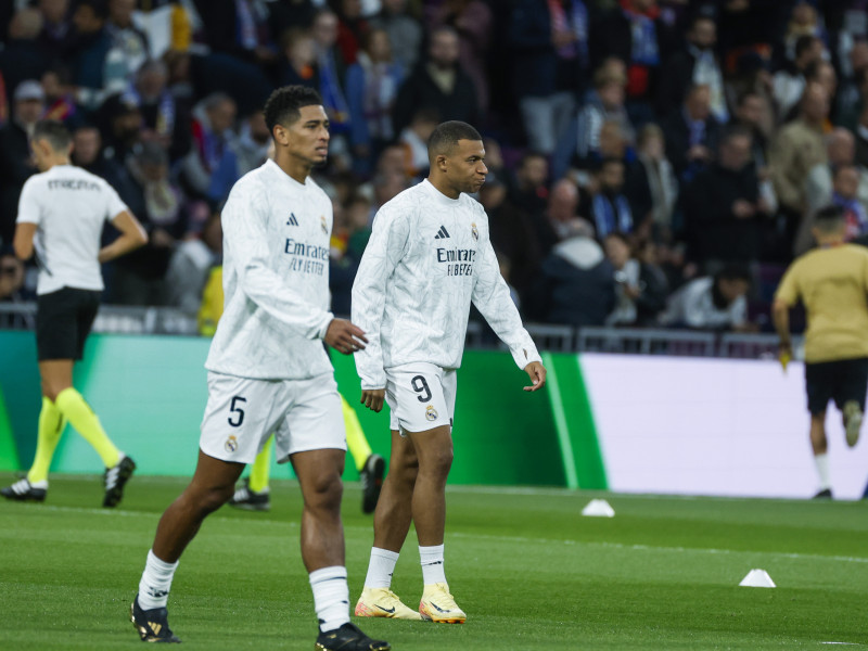 El delantero francés Kylian Mbappé (d) y el centrocampista británico Jude Bellingham del Real Madrid calienta este sábado, previo al partido de la jornada 11 de LaLiga EA Sports, entre el Real Madrid y el FC Barcelona, en el estadio Santiago Bernabéu de Madrid.