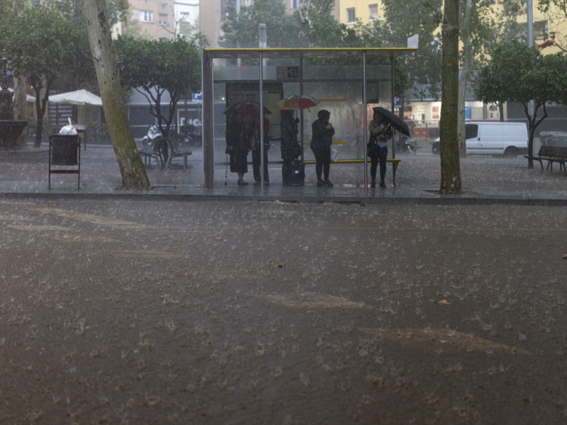 Varias personas esperan en la parada del bus durante la tormenta, a 30 de octubre de 2024, en Barcelona, Catalunya