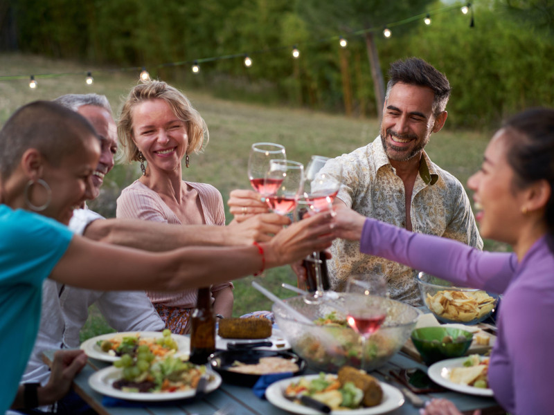 Grupo de amigos de mediana edad cenando juntos en la terraza de una casa o restaurante.