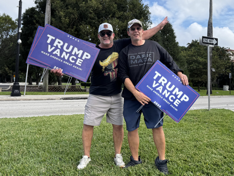 Dos simpatizantes del expresidente y candidato republicano Donald Trump muestran carteles de apoyo al candidato, este martes en Palm Beach, Florida (Estados Unidos).