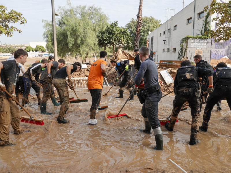 Voluntarios y fuerzas de seguridad trabajan para despejar una calle de Paiporta