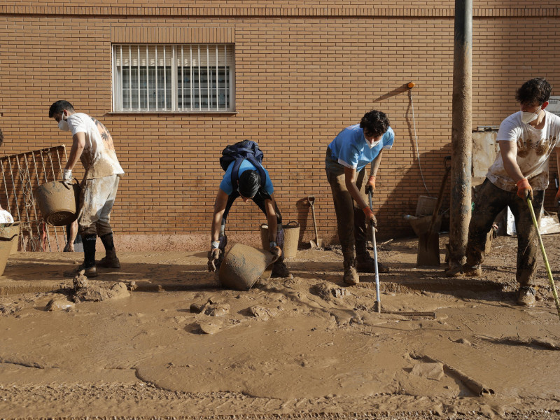 Varios jóvenes trabajan para despejar una calle de Paiporta