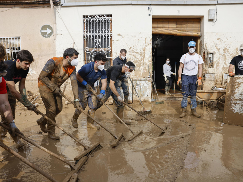 Voluntarios barren el lodo de una calle de Masanasa