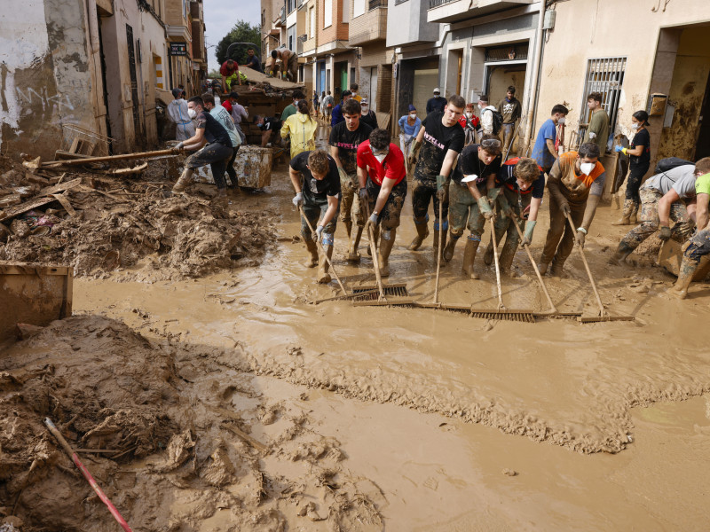 Voluntarios barren el lodo de una calle de Masanasa