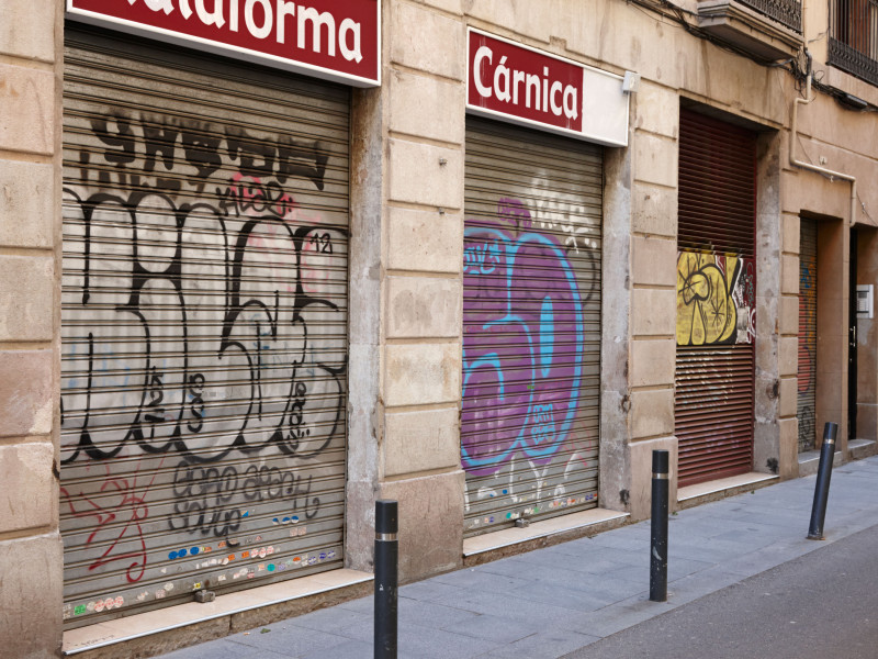 Grafitis en las persianas de las tiendas cerradas en el centro histórico de Barcelona, ​​Cataluña, España